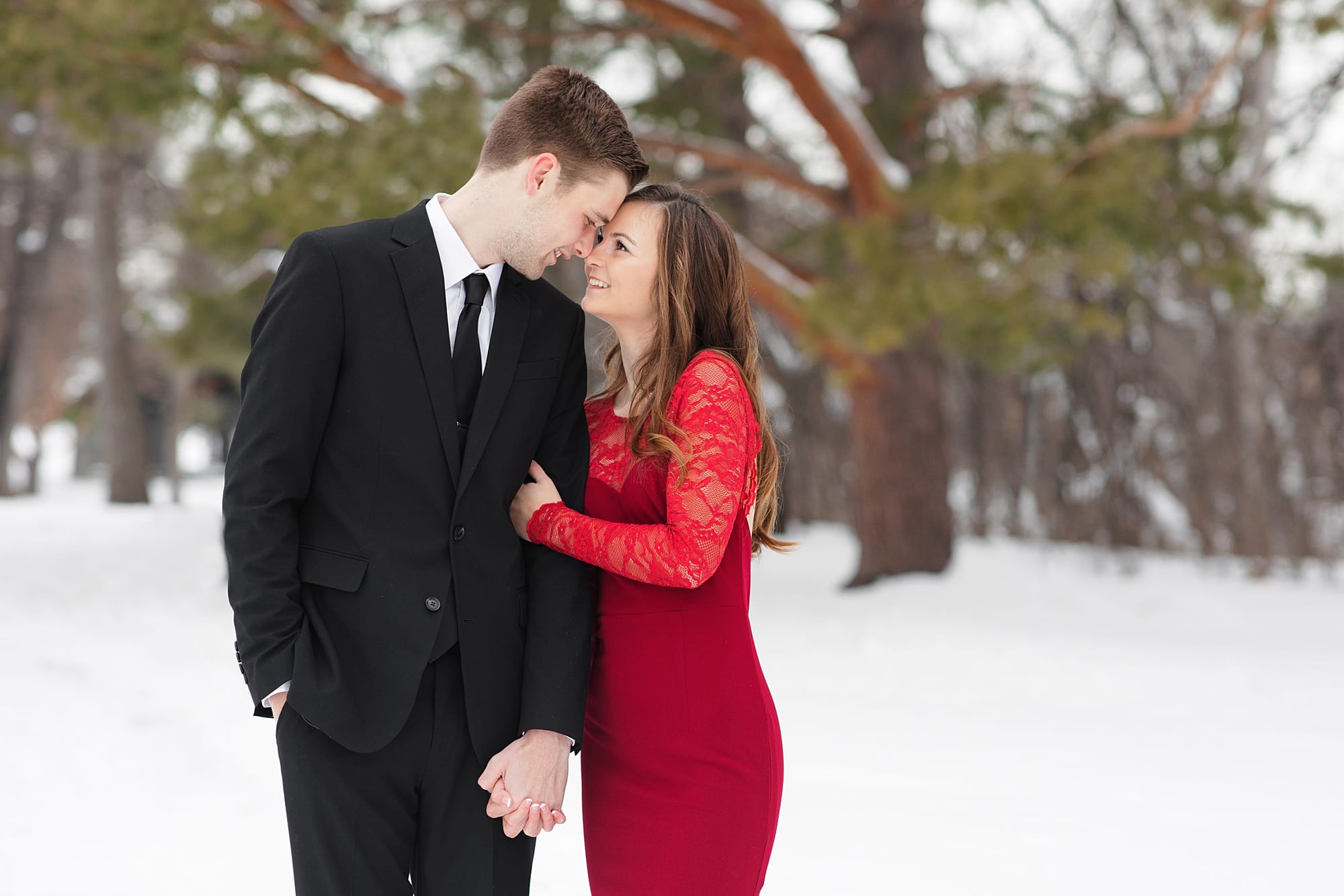 Engaged couple hold hands and smile during their winter engagement session in Gooseberry Park