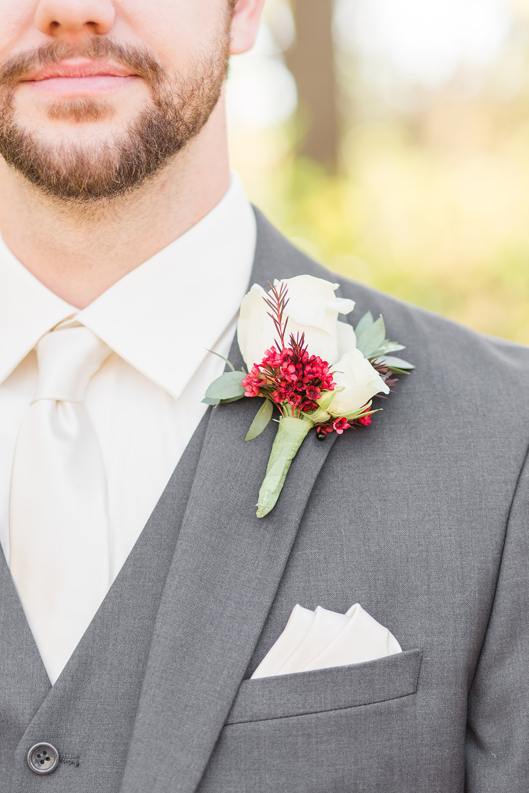 A groom with a white tie and white and red wedding boutonnieres