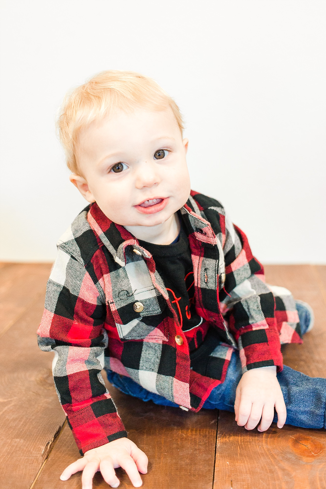 One year old in Flannel smiles at the camera