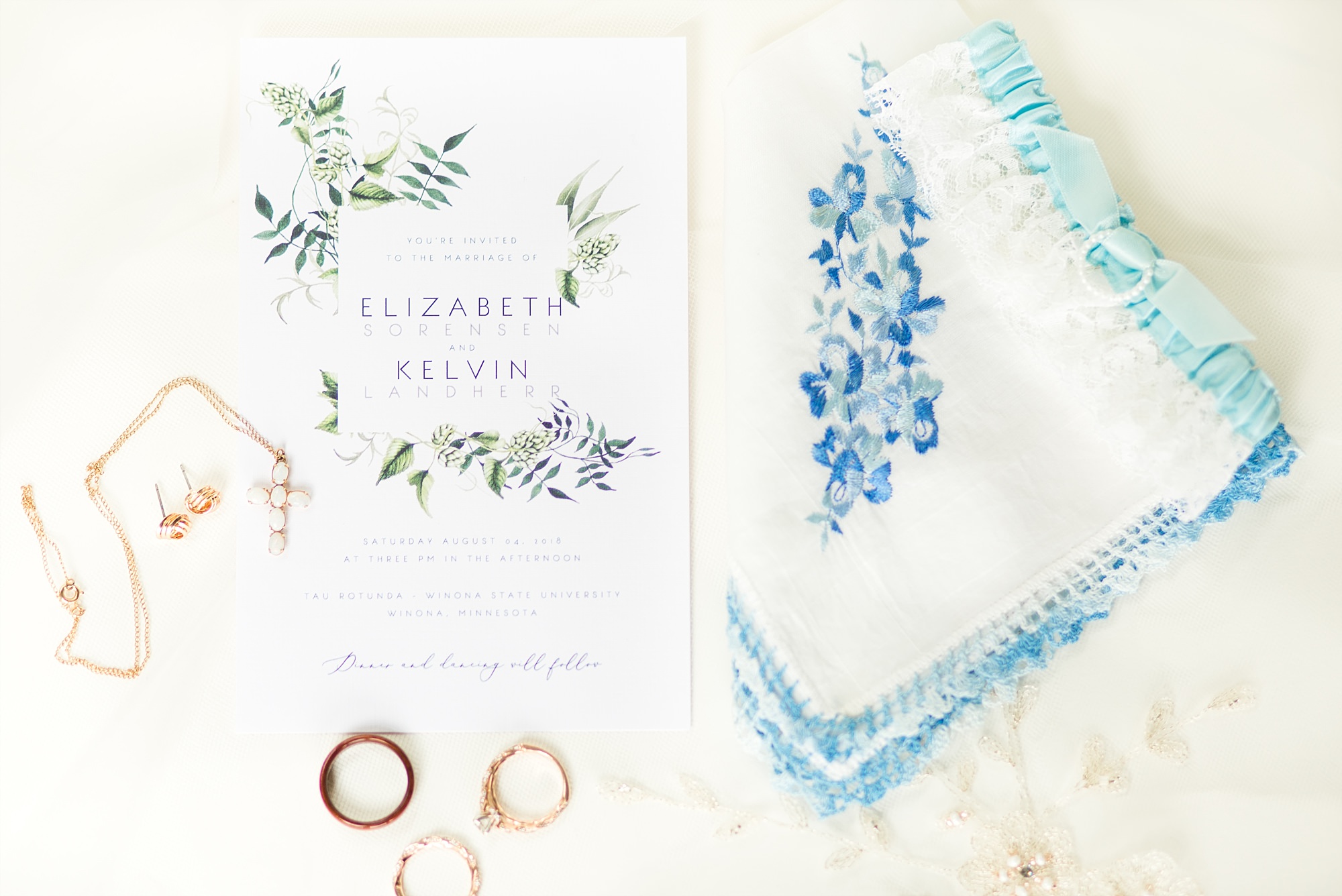 Wedding detail flatlay with blues, greens, and rose gold