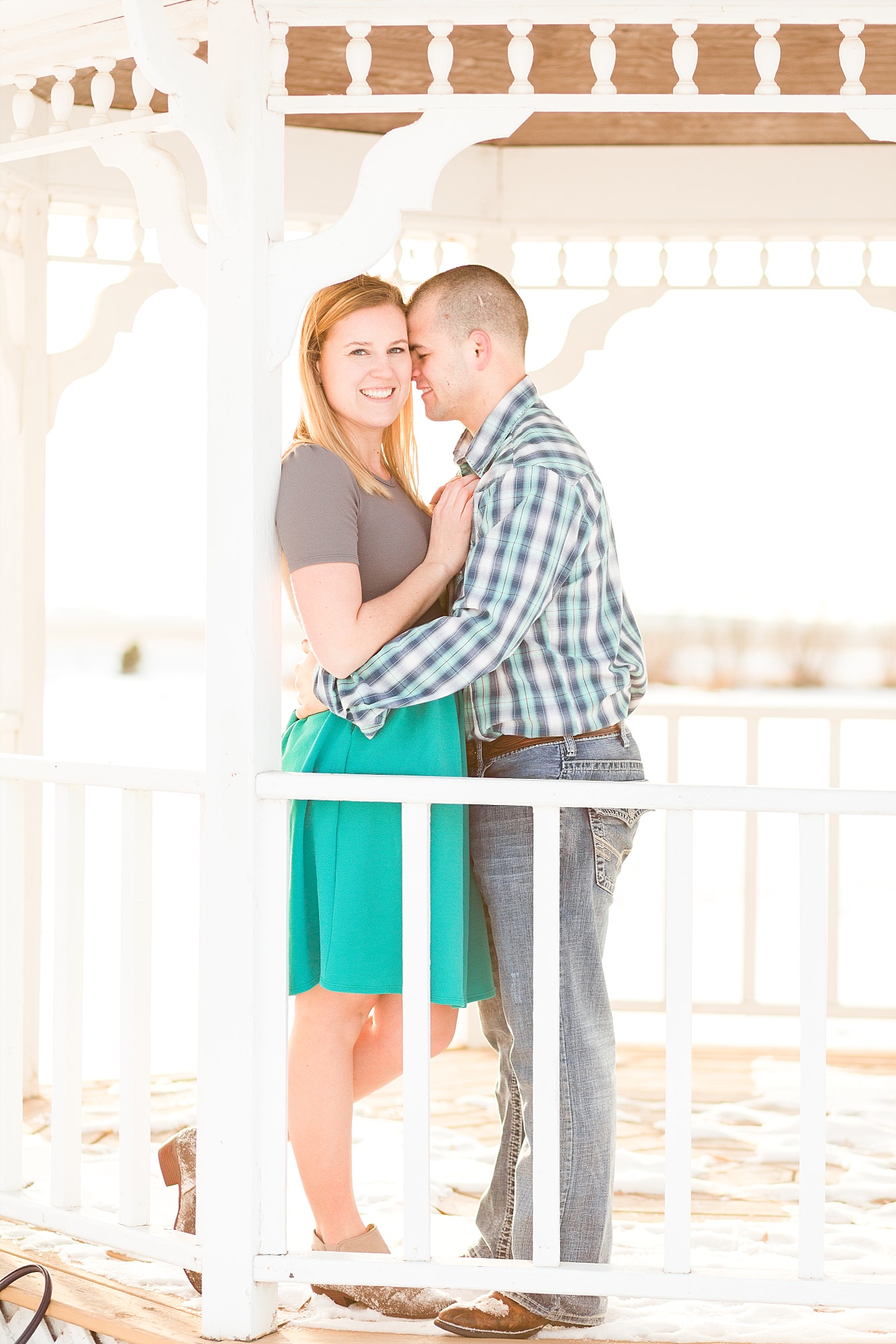 Engaged couple smile under a white gazebo at A Friend's House