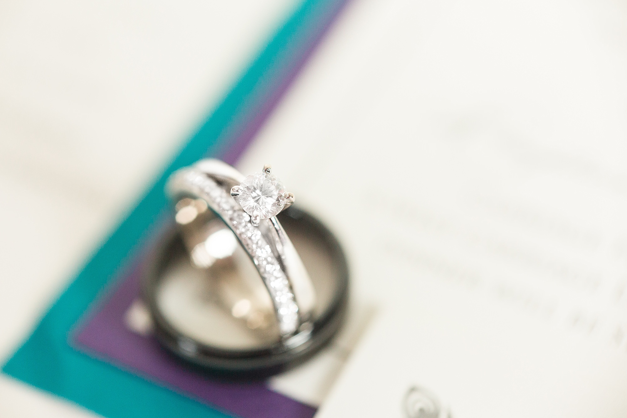 Detail shot of wedding bands on blue and purple wedding invites