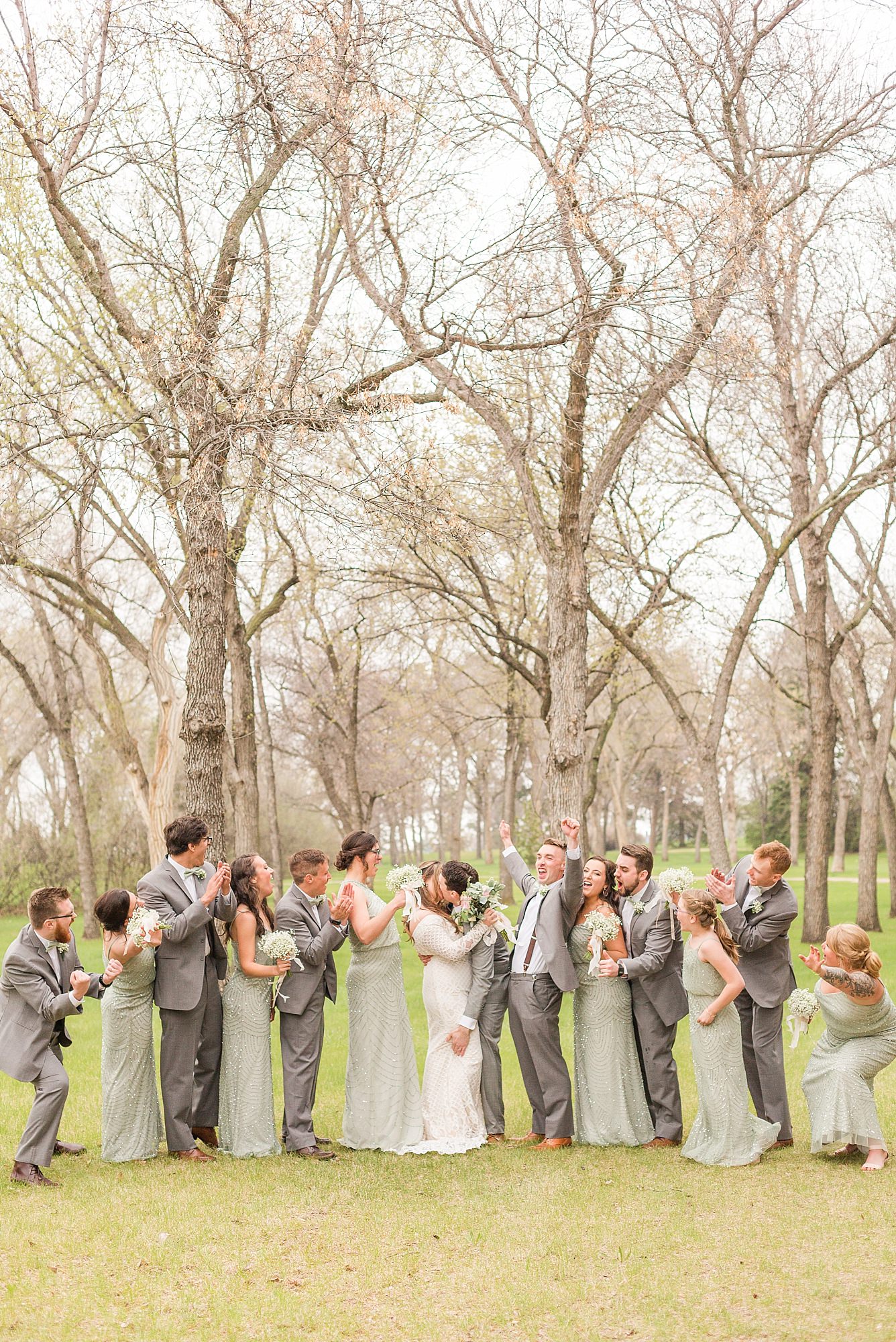 A wedding party in sea-foam green and grey cheer for the newlyweds