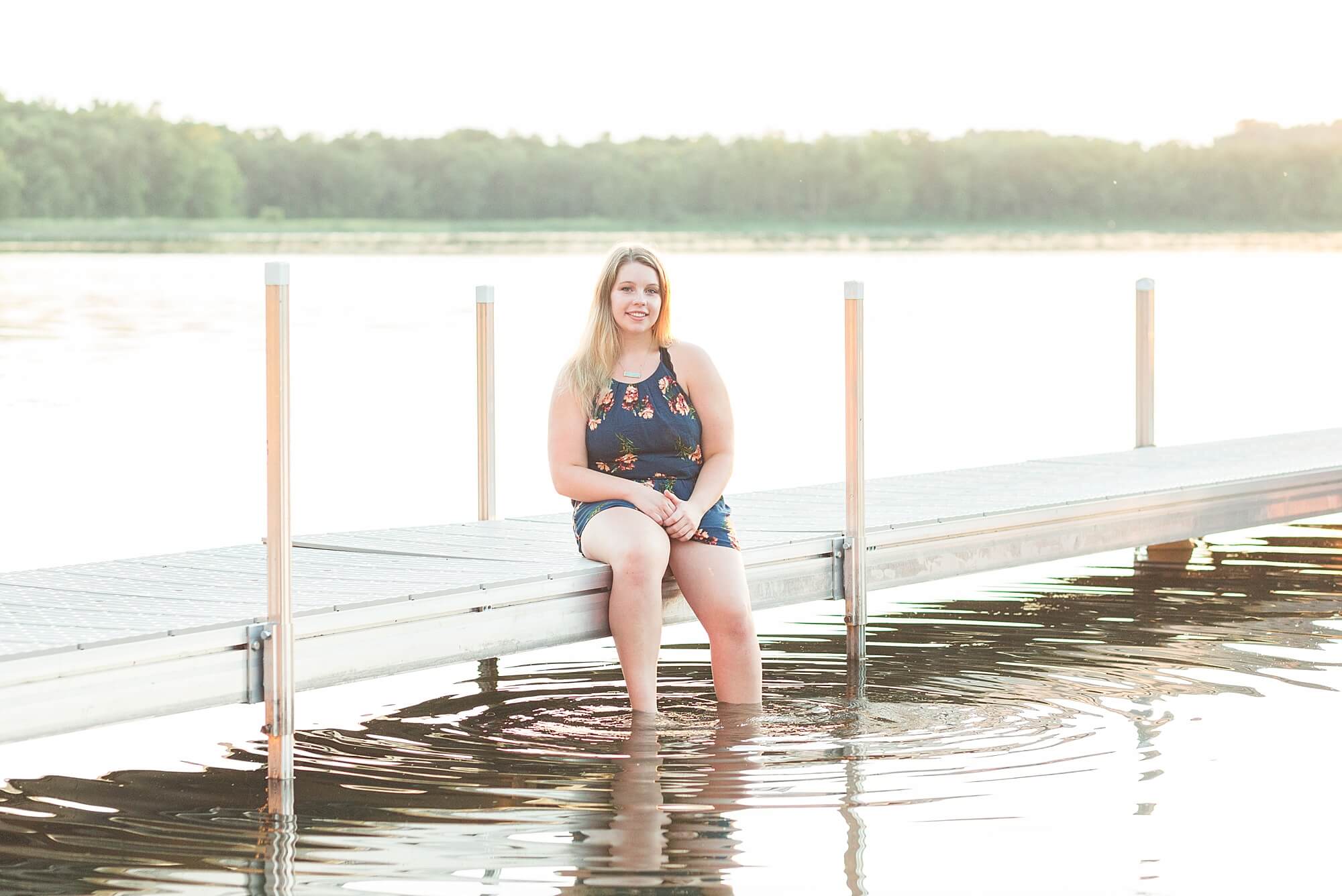 A high school senior dips her feet in the water during her Lakeside Senior Portrait Session