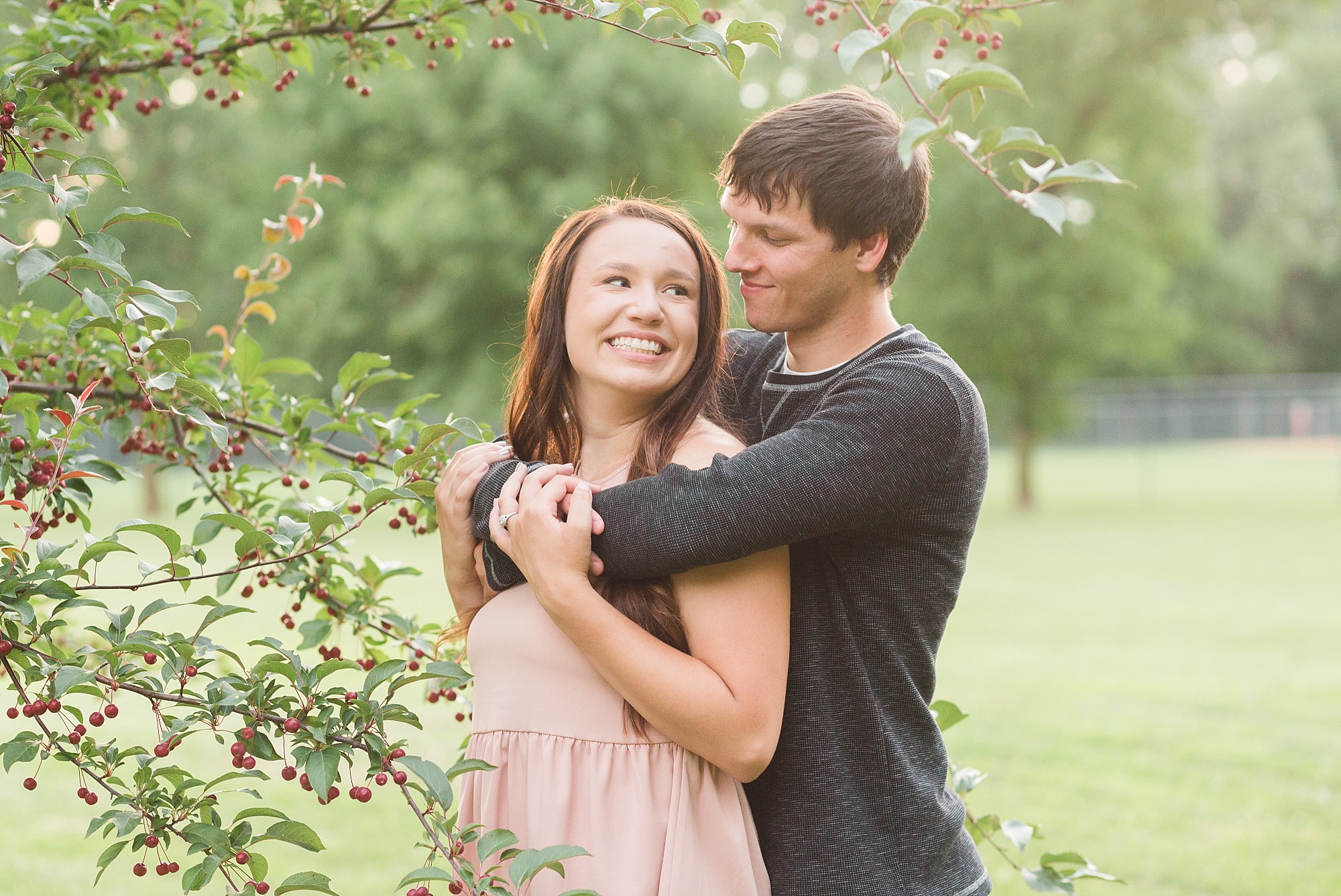 A couple smile at each other near a berry tree during their elmwood park engagement session