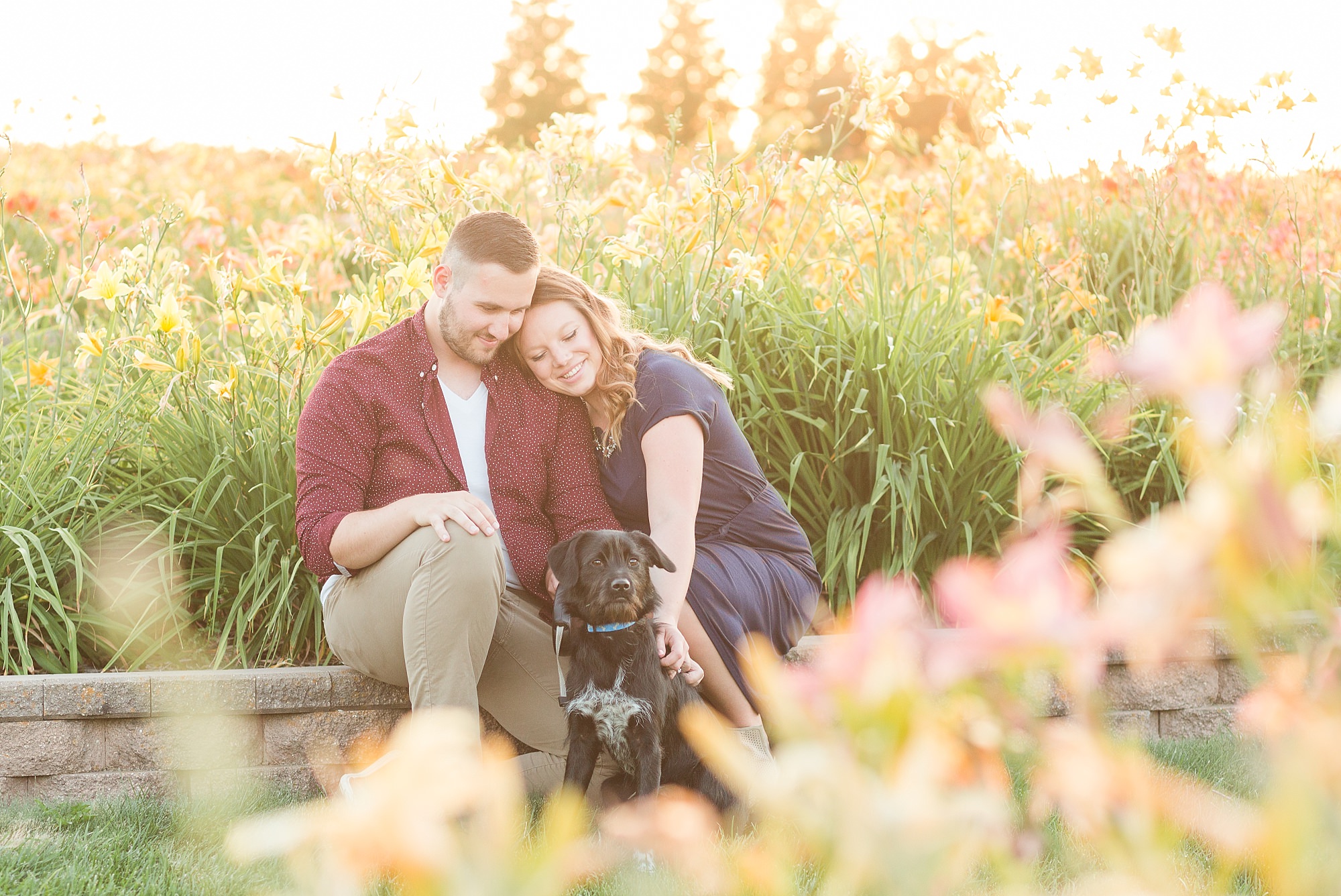 An engaged couple and their dog enjoy the sunset at the NDSU flower garden