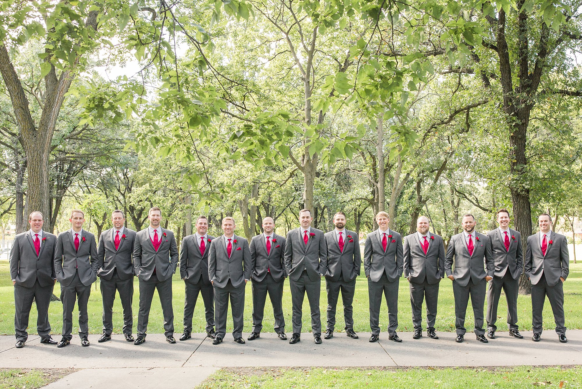 A large group of groomsmen with grey suits and red ties