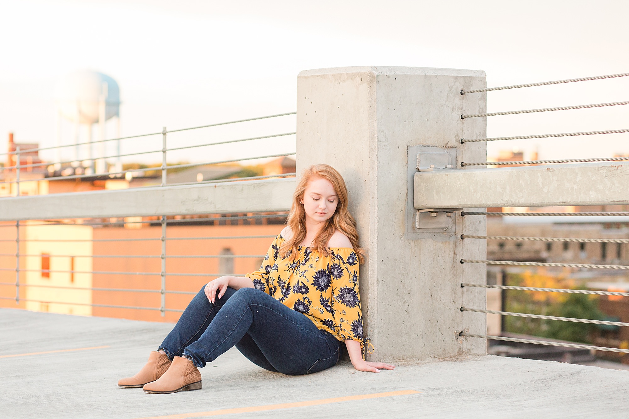 High school senior at the top of a Downtown Fargo parking ramp in blue and yellow floral and jeans