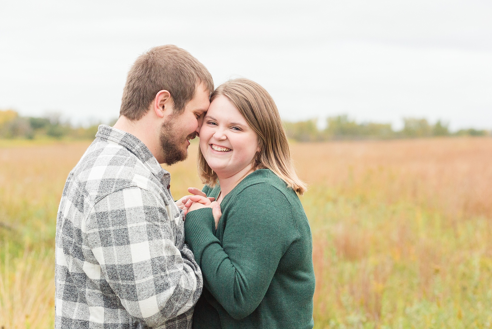 A couple smile and holds hands during their engagement session at Buffalo River State Park