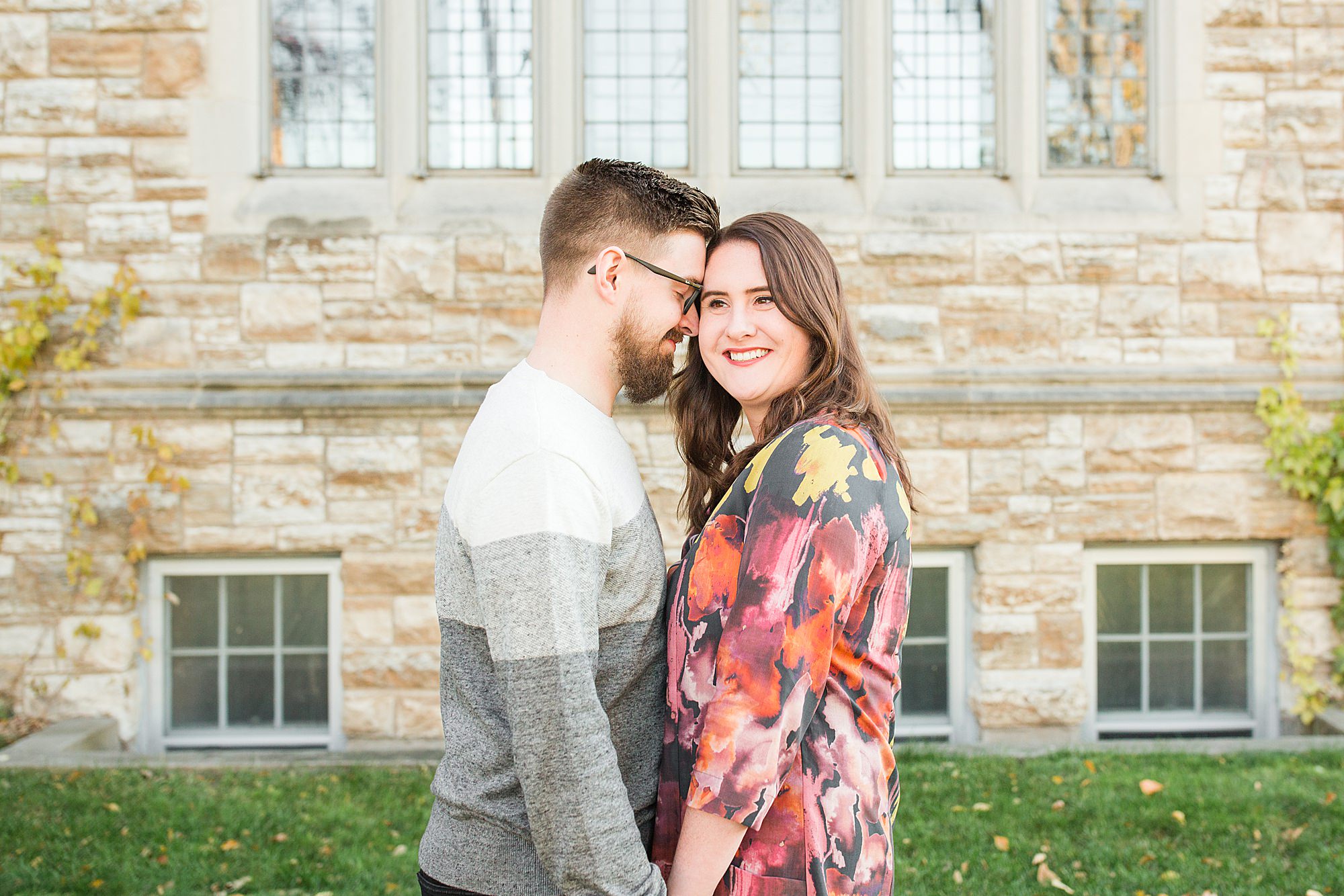 Engaged couple smile in front of a brick church in Downtown Fargo