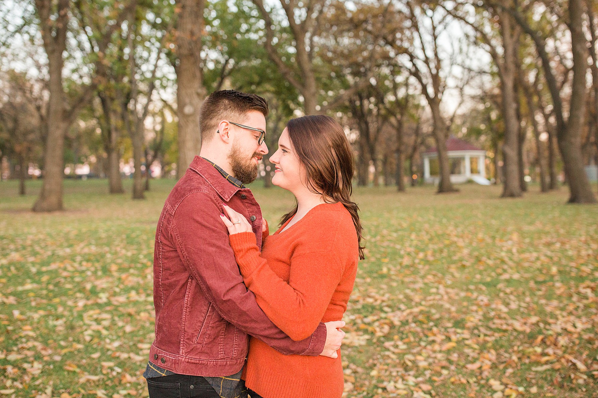 Couple in warm colors go in for a kiss during their colorful fall engagement session