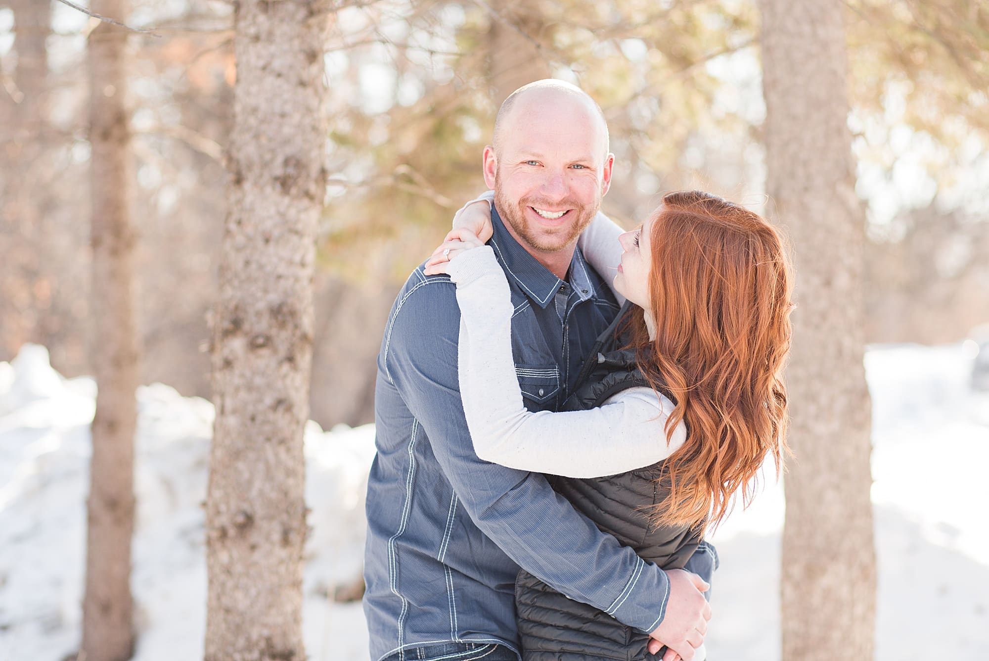 A redhead smiles up to her fiance during their sunny winter engagement session