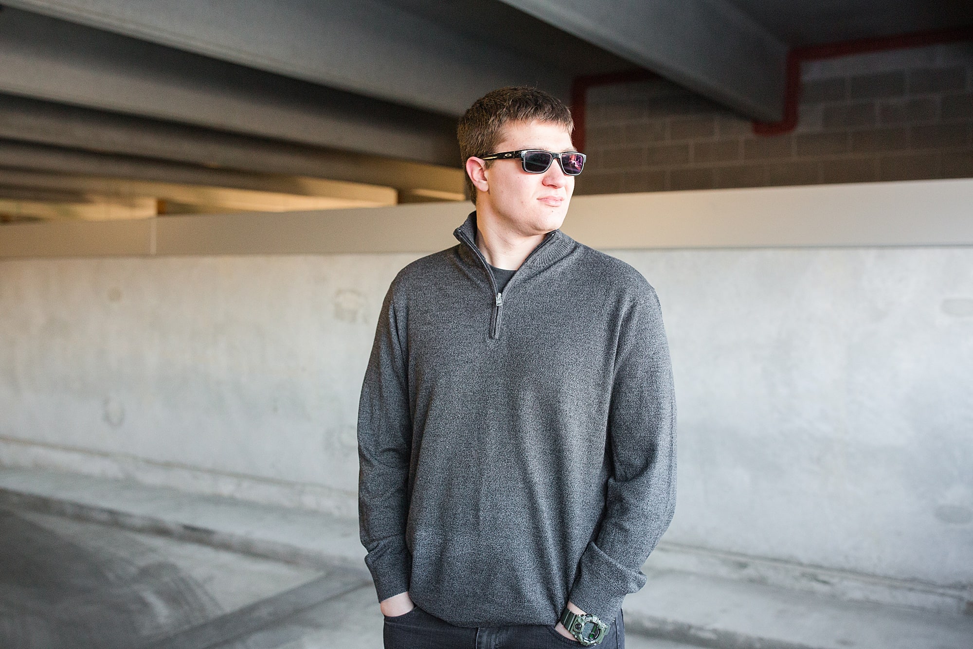 A high school senior in grey and blank looks over his shoulder at a Downtown Fargo Parking Ramp
