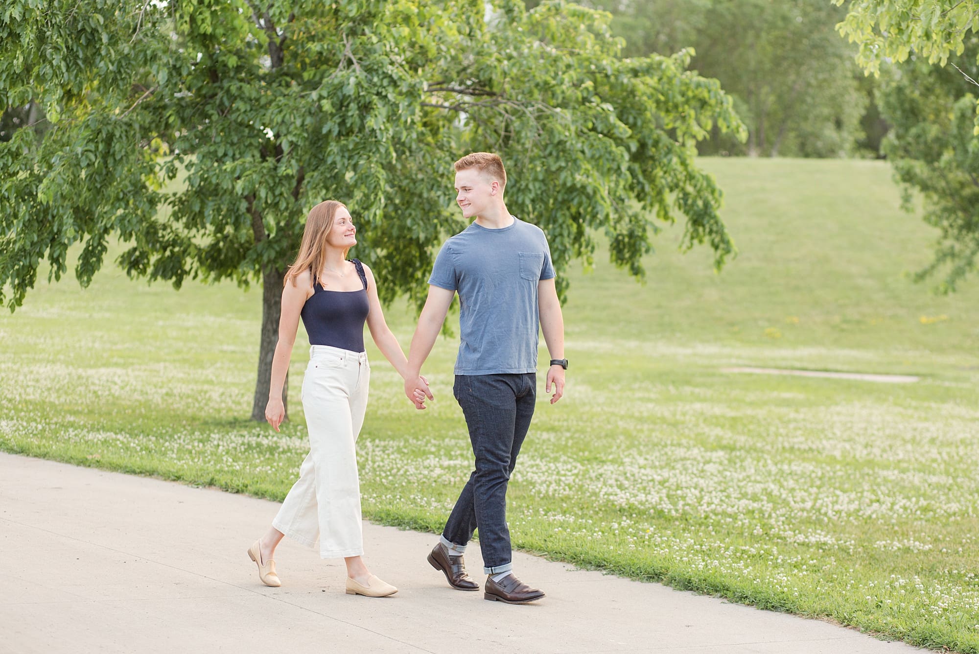 An engaged couple walk down the walkway in Wildflower Grove Park for their engagement session