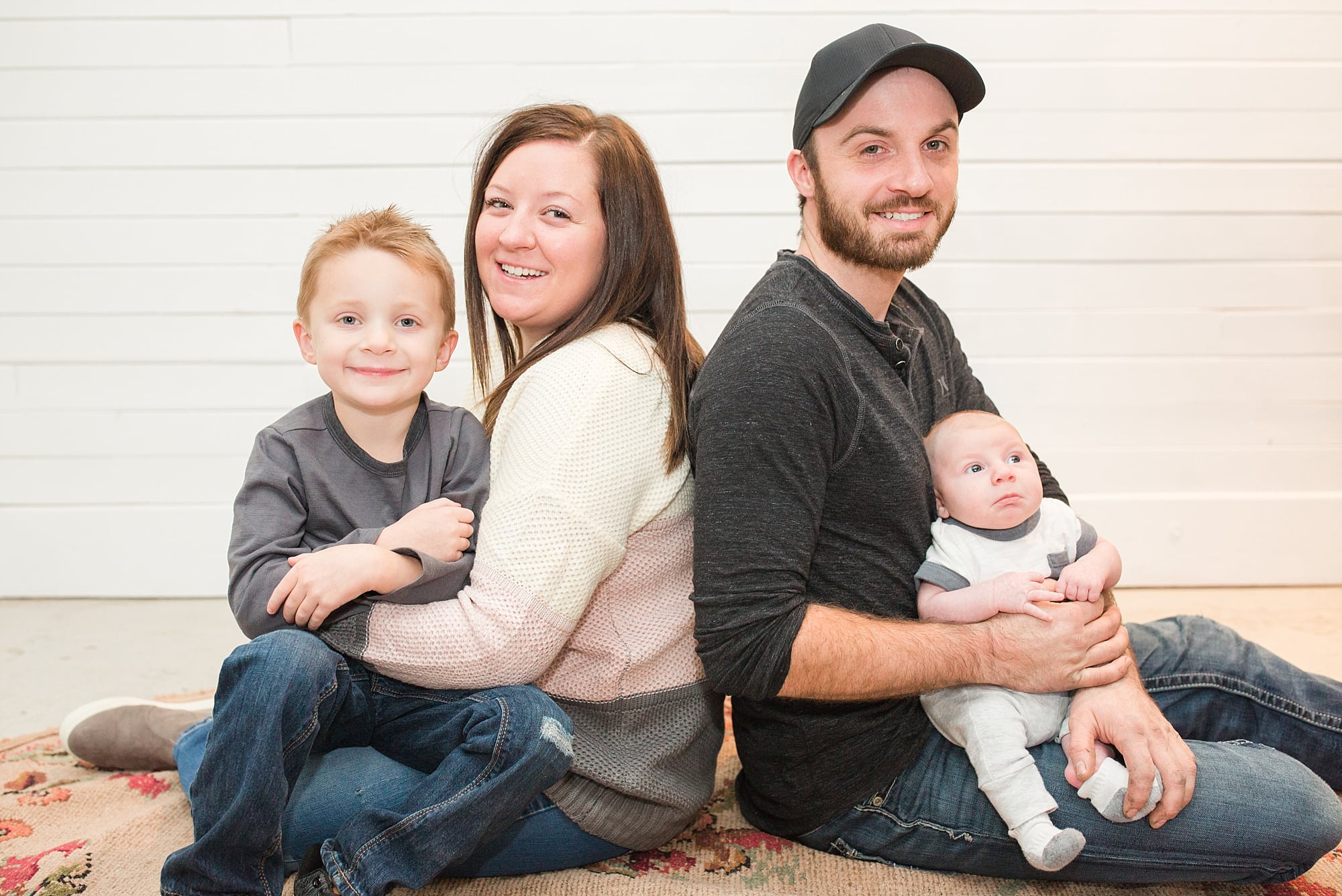 Parents holding their young boys smile during their indoor family session in Fargo