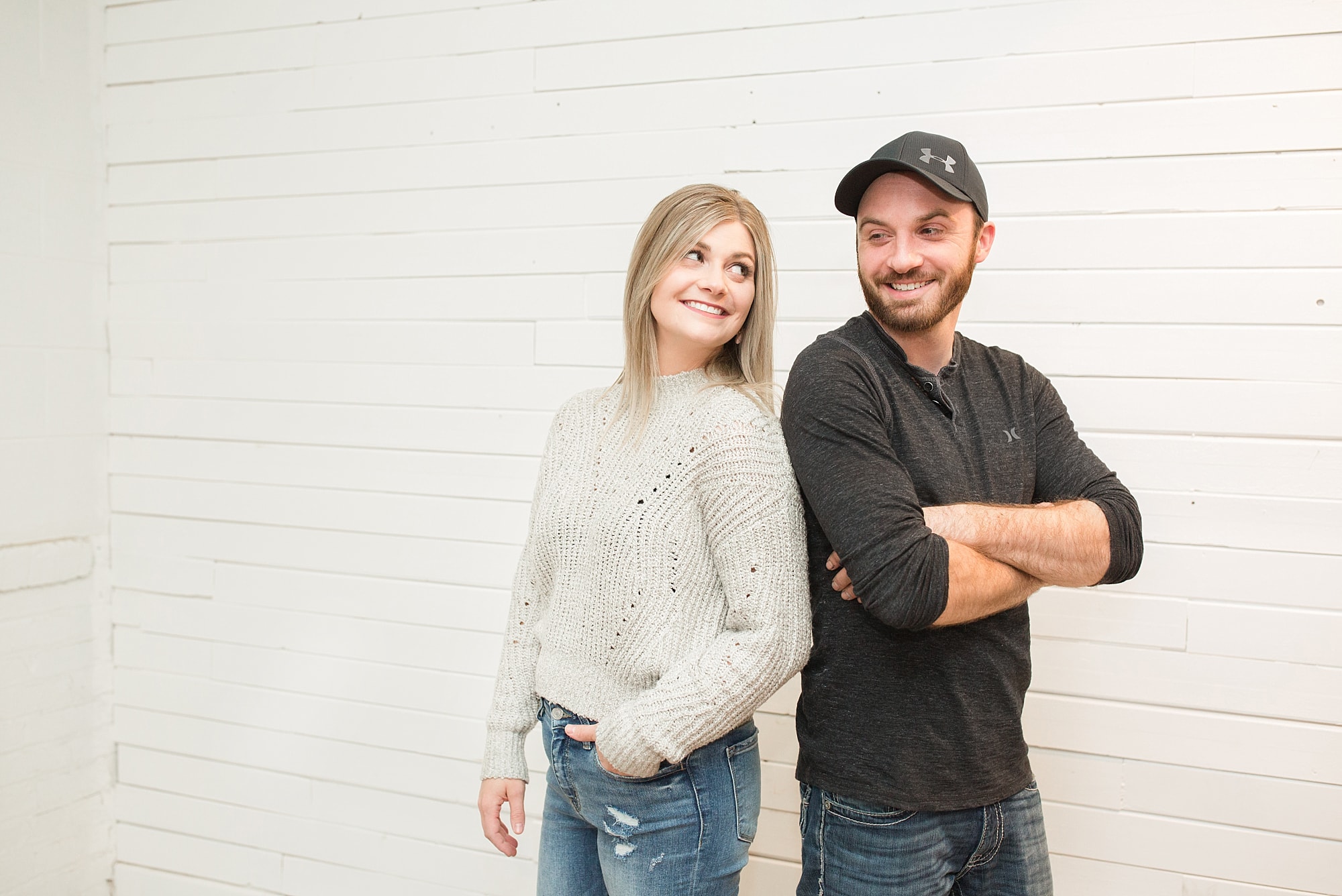Adult brother and sister lean back to back and smile at each other in a Fargo photo studio