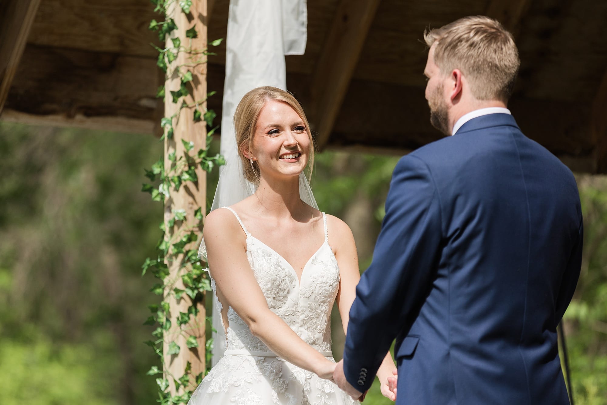 Bride smiles at her groom during their outdoor summer wedding ceremony