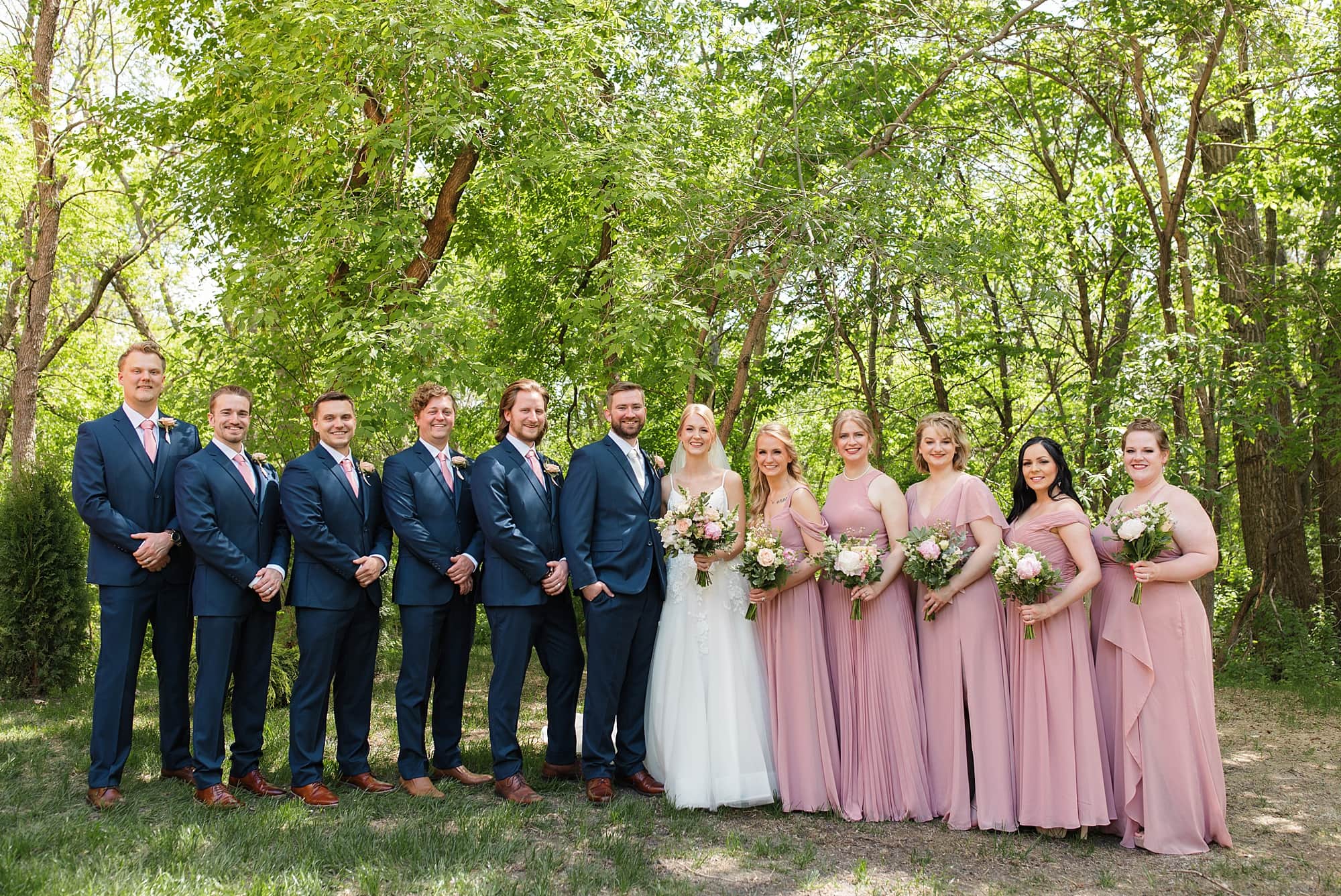 Wedding party in navy and soft pink smile for photos at  Romantic Moons Event Center