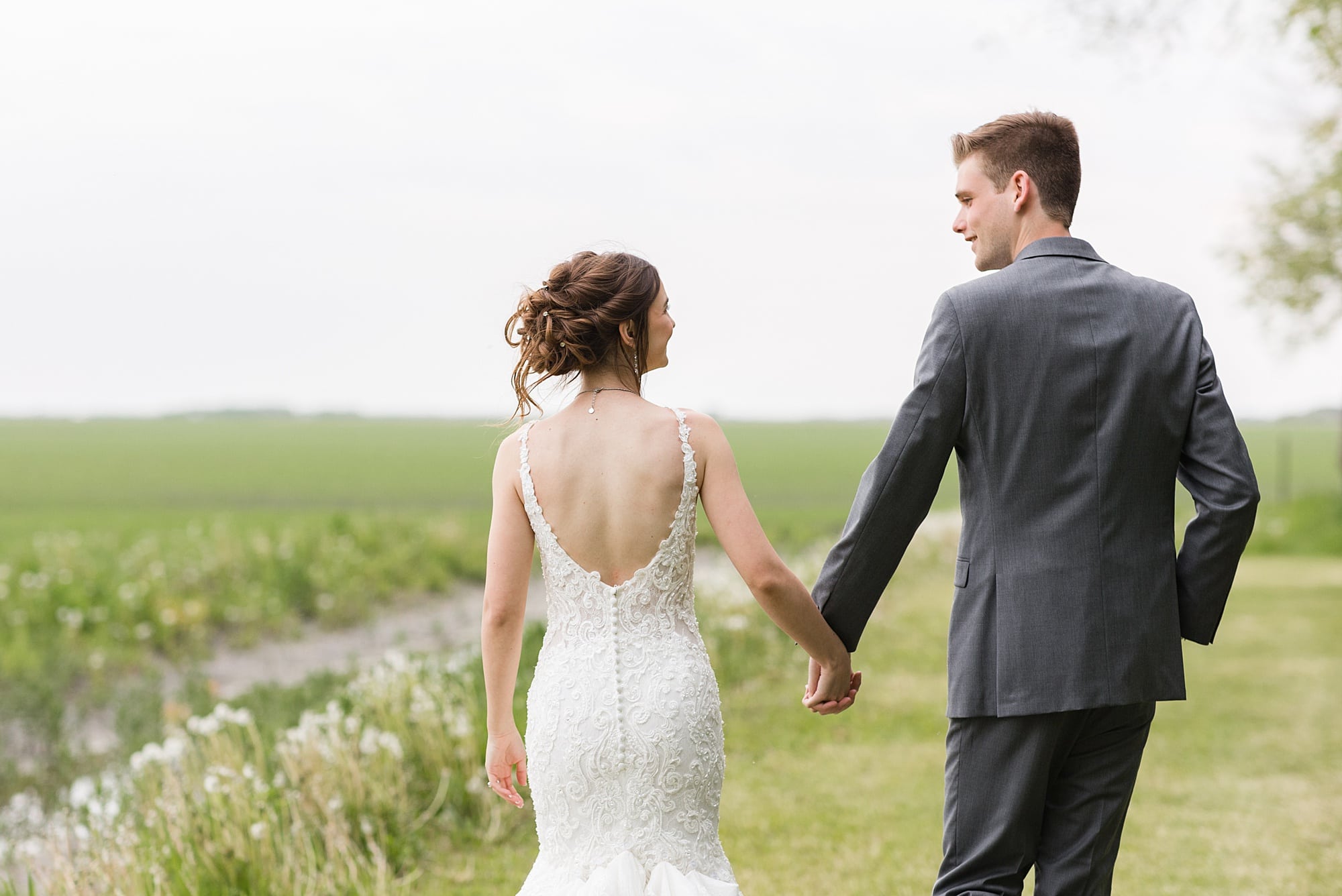 Bride and groom hold hands and walk during their sunset photos at Legacy Acres Events