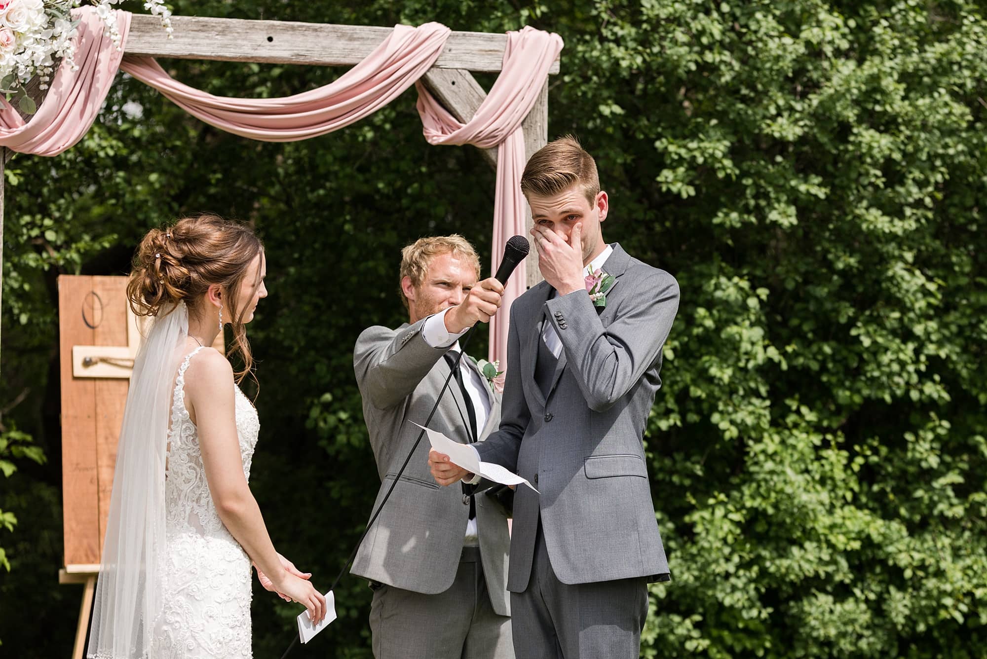 Groom wipes away tears during the outdoor wedding ceremony at Legacy Acres Events