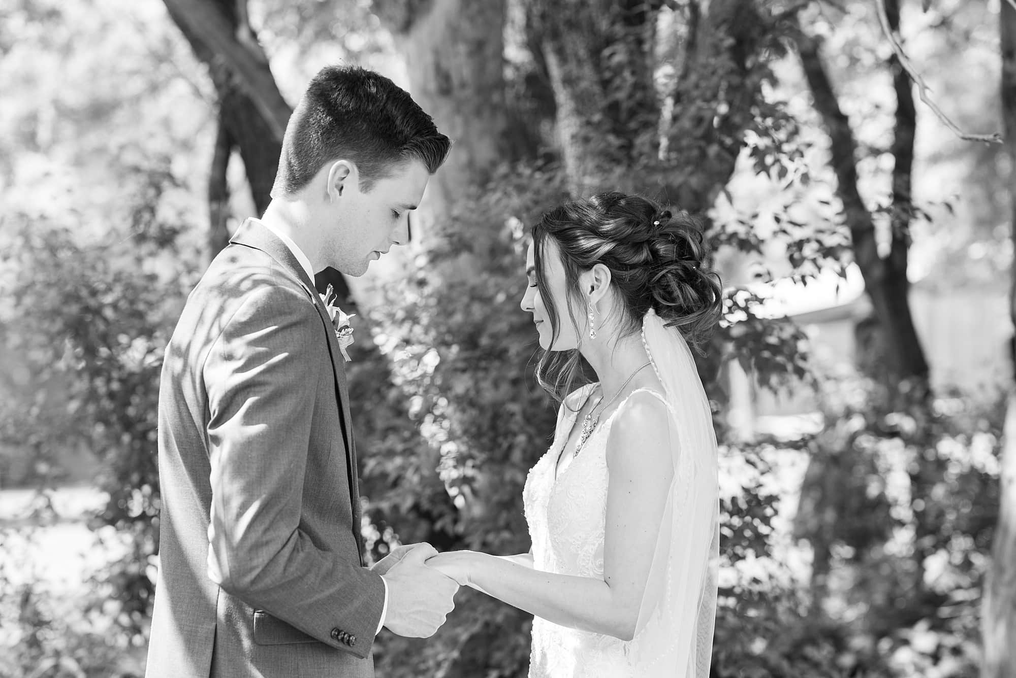 Bride and groom pray together during their first look at Legacy Acres Events