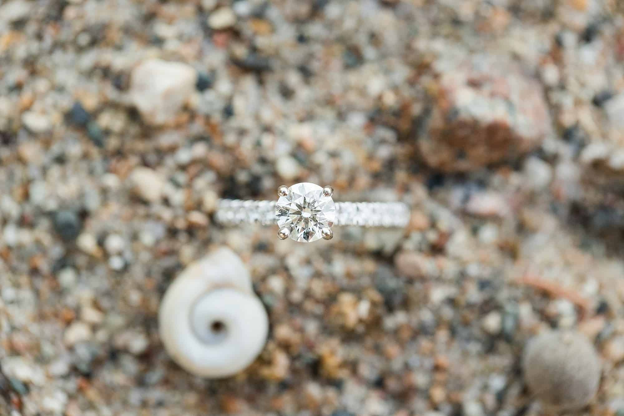 White gold diamond engagement ring against the beach sand at Cotton Lake