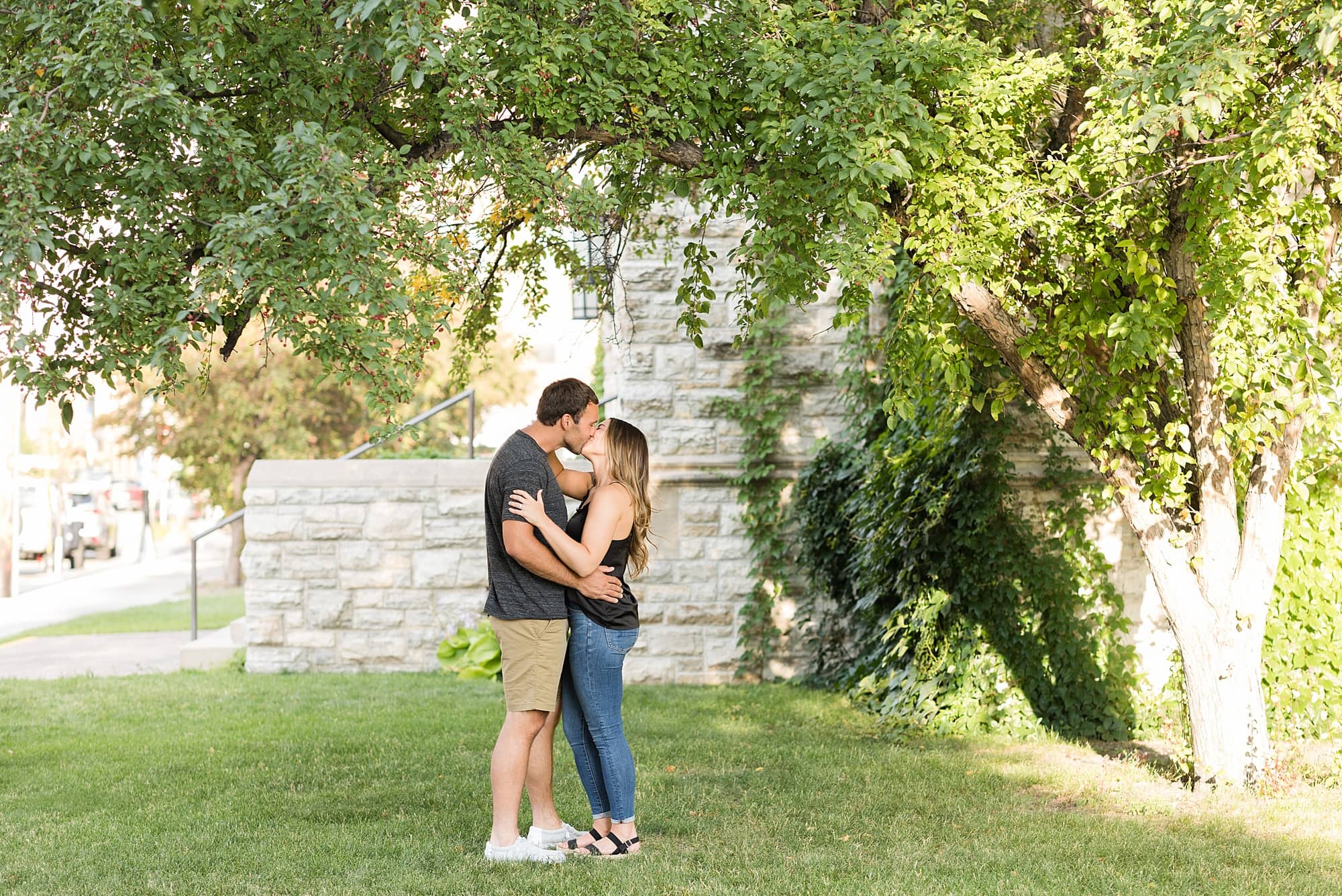 An engaged couple kissing under a tree during their engagement session in Downtown Fargo