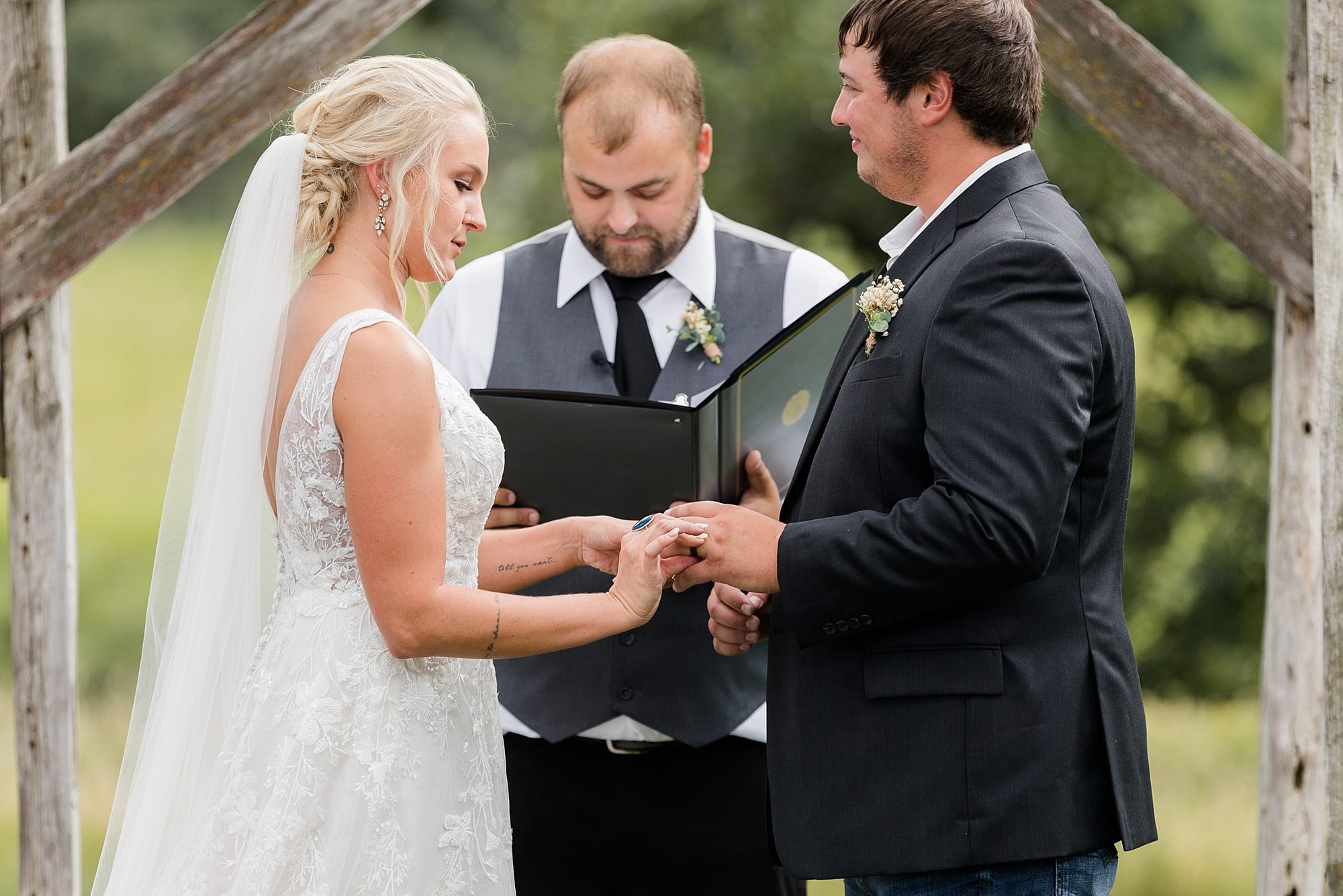 Bride and Groom exchange rings during their outdoor  summer wedding at Rustic Oaks