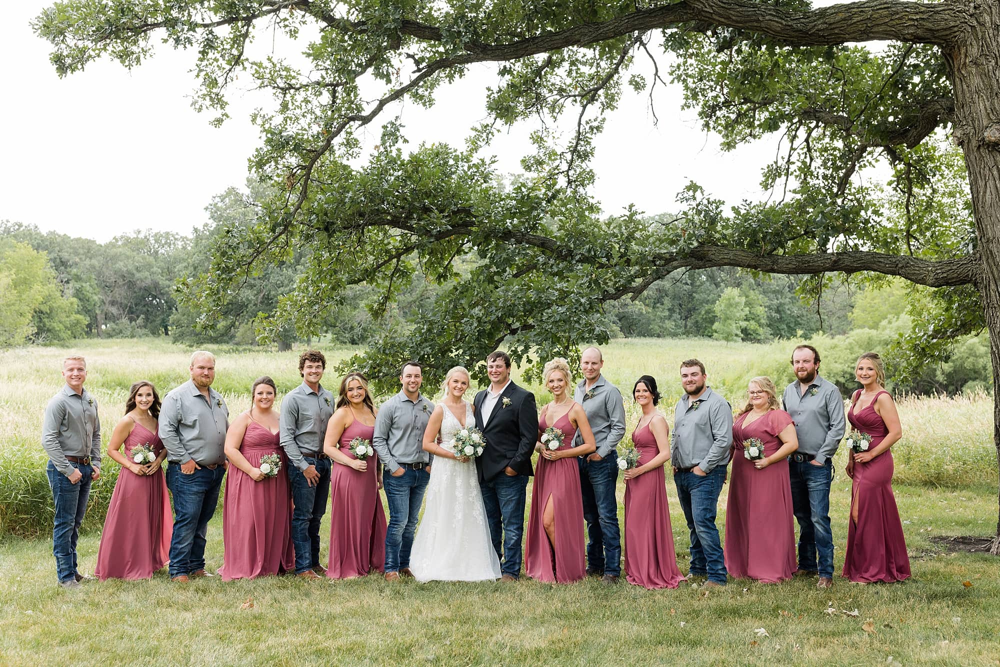 Full bridal party in mauve and grey smile at Rustic Oaks