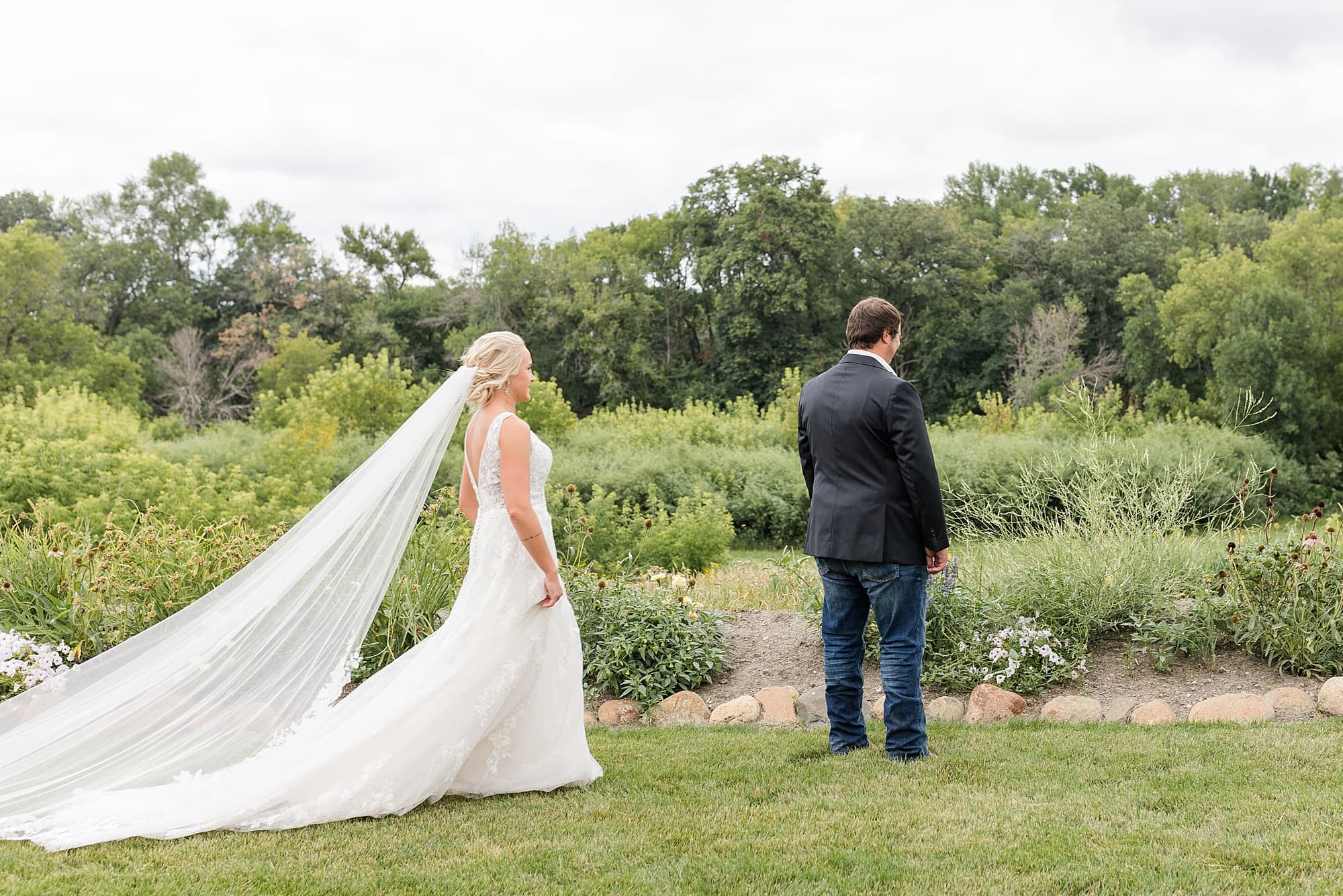 A bride walks up to her groom for their first look at their  summer wedding at Rustic Oaks