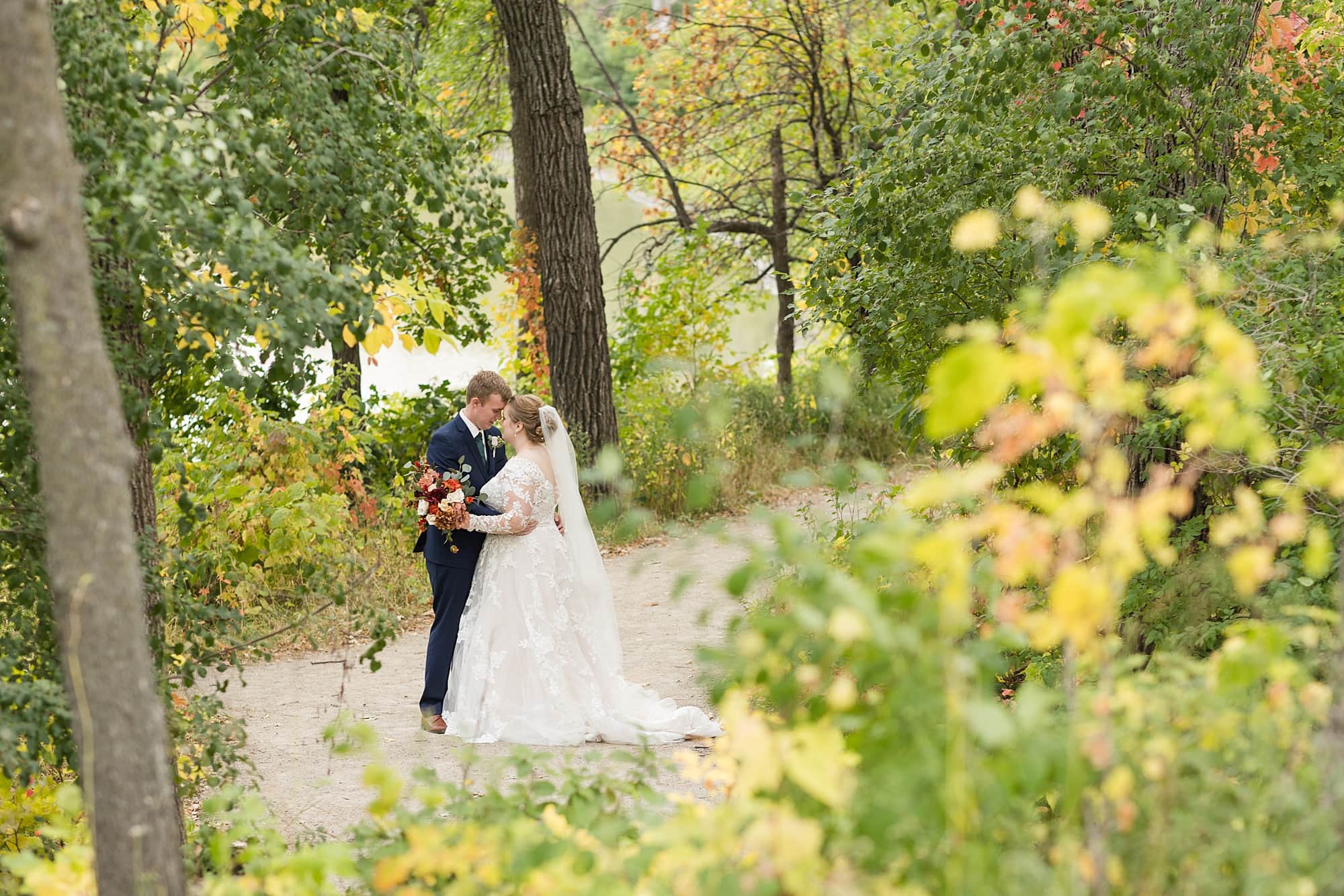 Bride and groom surrounded by fall colors at Orchard Glen Park in Fargo, ND