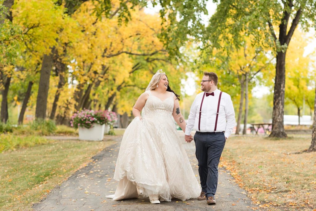 Bride and Groom walk through Chahinkapa Park in the fall holding hands