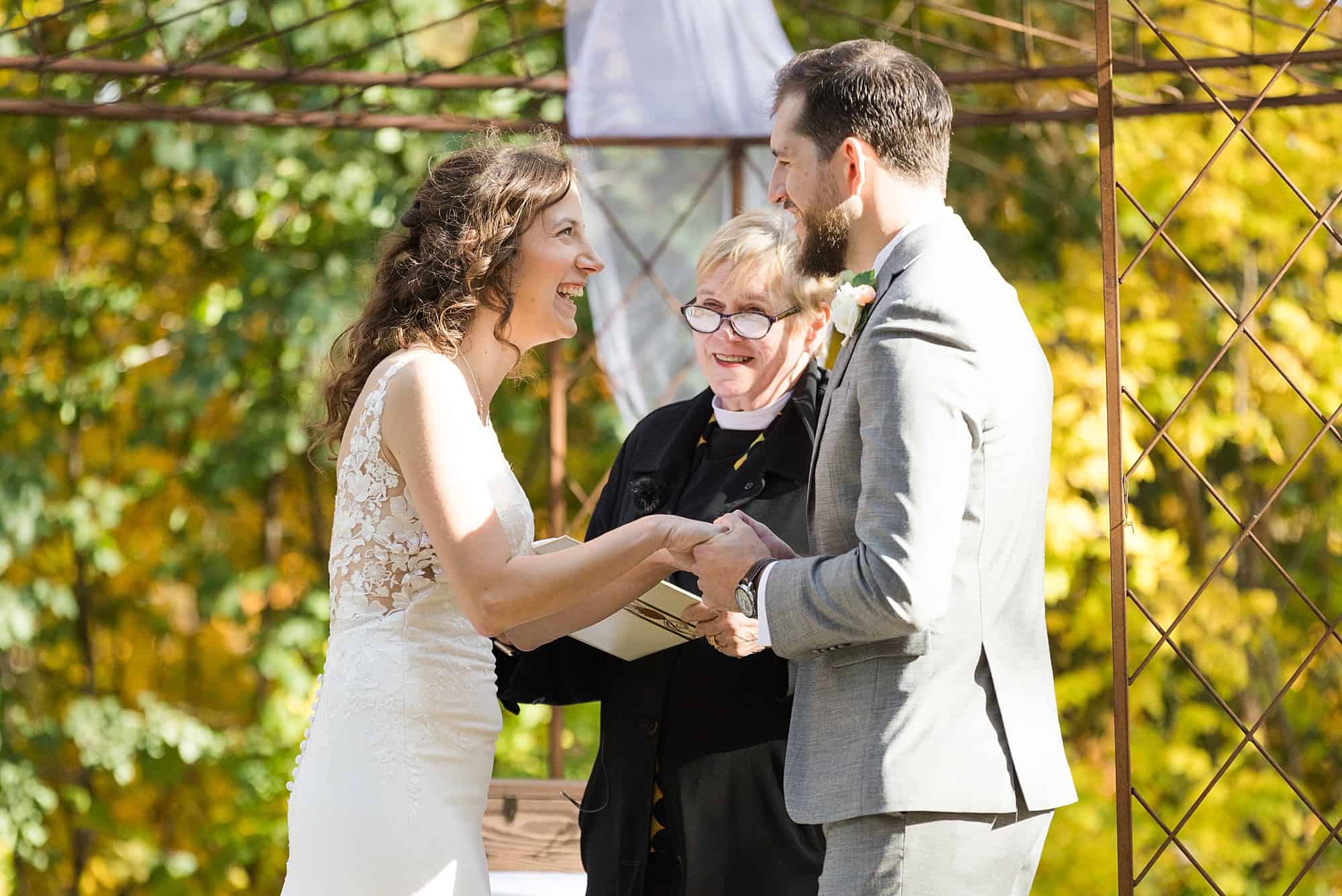 Bride and groom laugh and hold hands during their outdoor fall wedding ceremony 