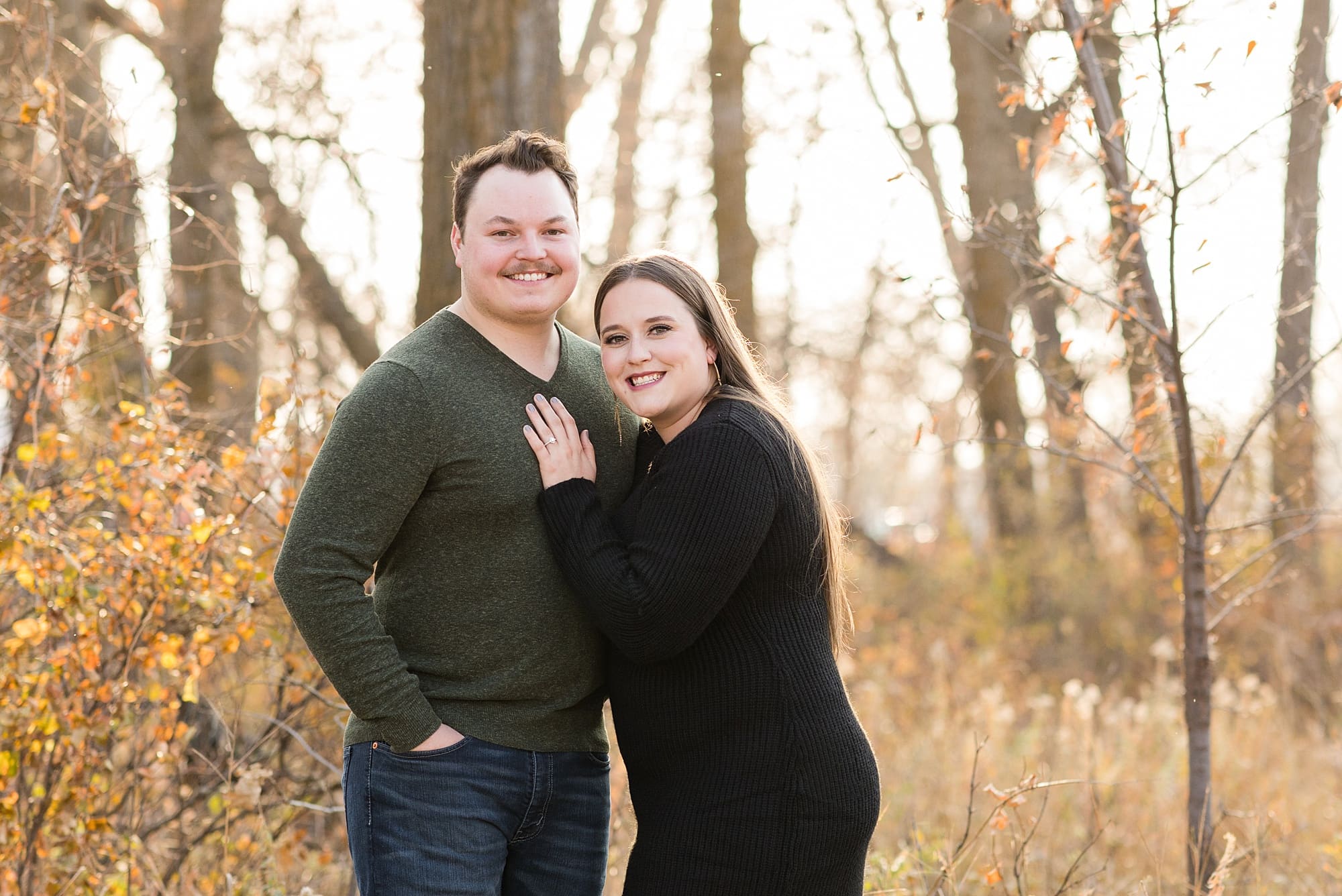 Engaged couple smiles at the camera and shows off their engagement ring during their Engagement Session at Sheyenne Grassland