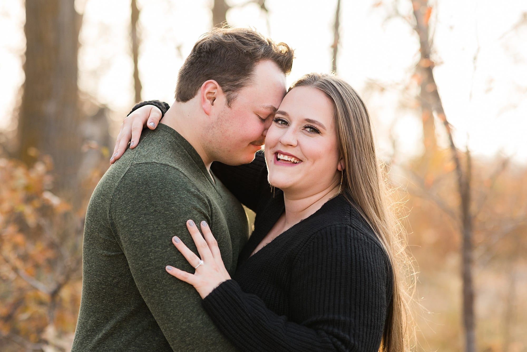 Guy leans into his fiance white she smiles during their Engagement Session at Sheyenne Grassland