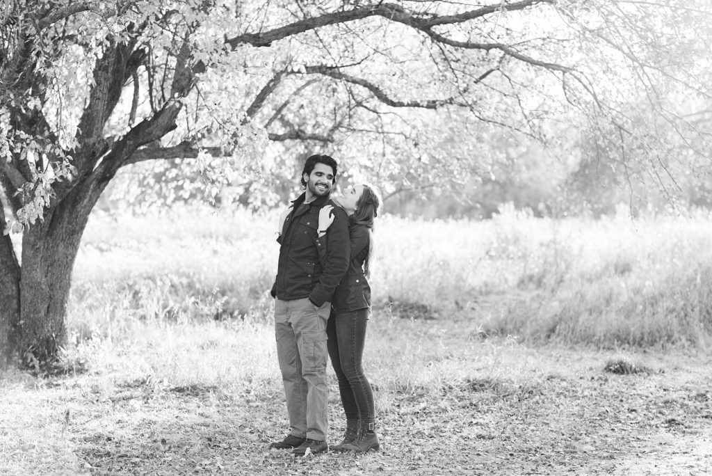 Black and white photo of a women hugging her fiance and smiling during their engagement session at Orchard Glen 