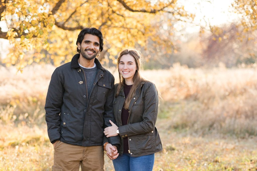 Engaged couple holds hands and smiles during their engagement session at Orchard Glen 