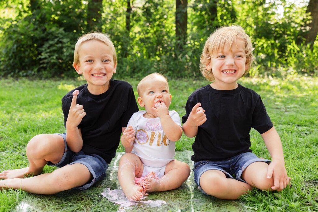 Siblings share a cake during a one year old cake smash at a family photos in Lindenwood Park