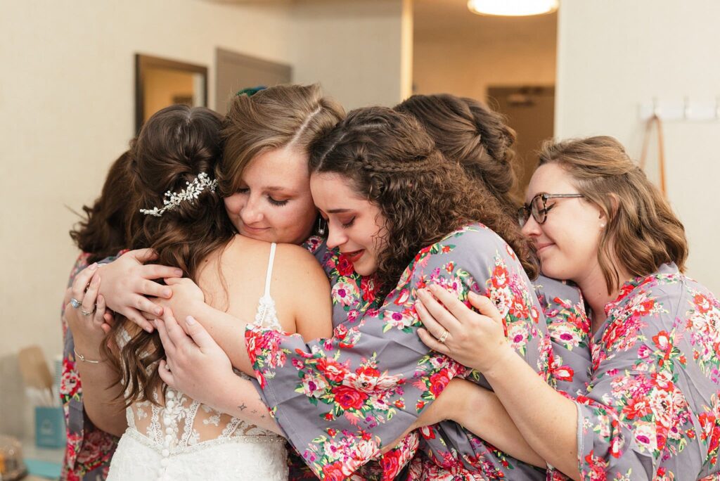 Best of 2023 Wedding Photography a wedding party hugs the bride after seeing her for the first time