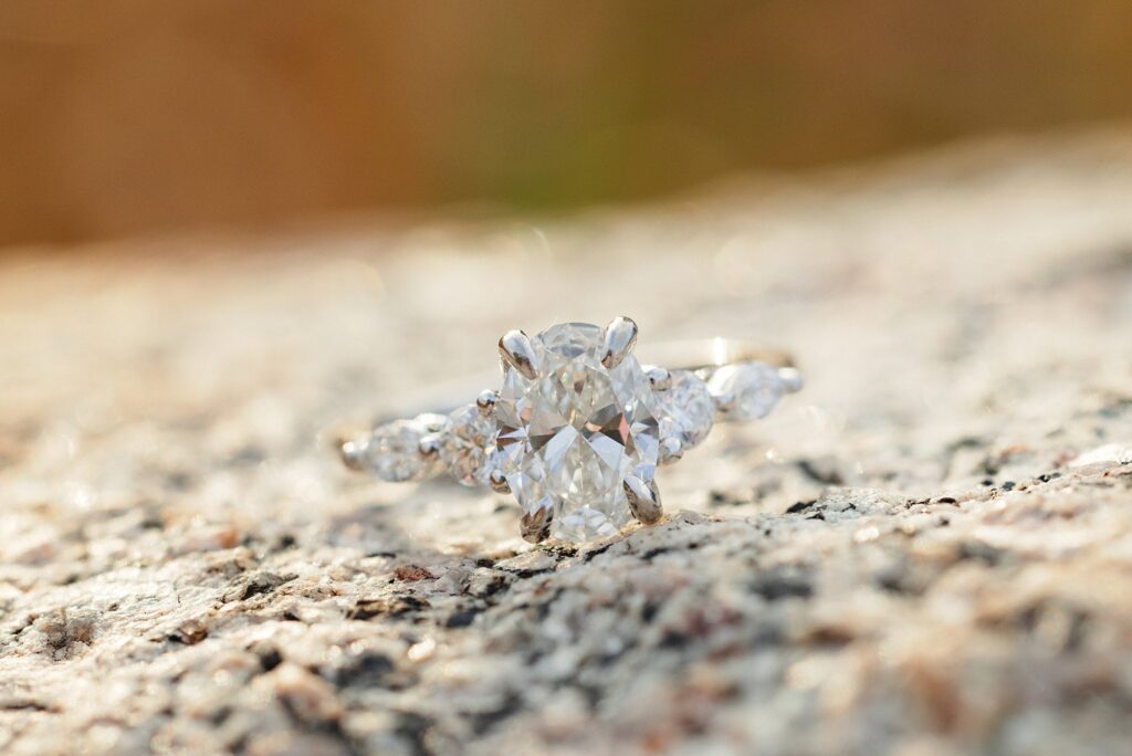 Engagement ring sits on a rock during sunset