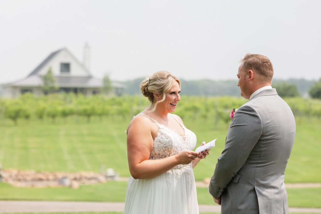 Bride reads vows privately to her groom with the orchard in the back at their wedding at Carlos Creek Winery
